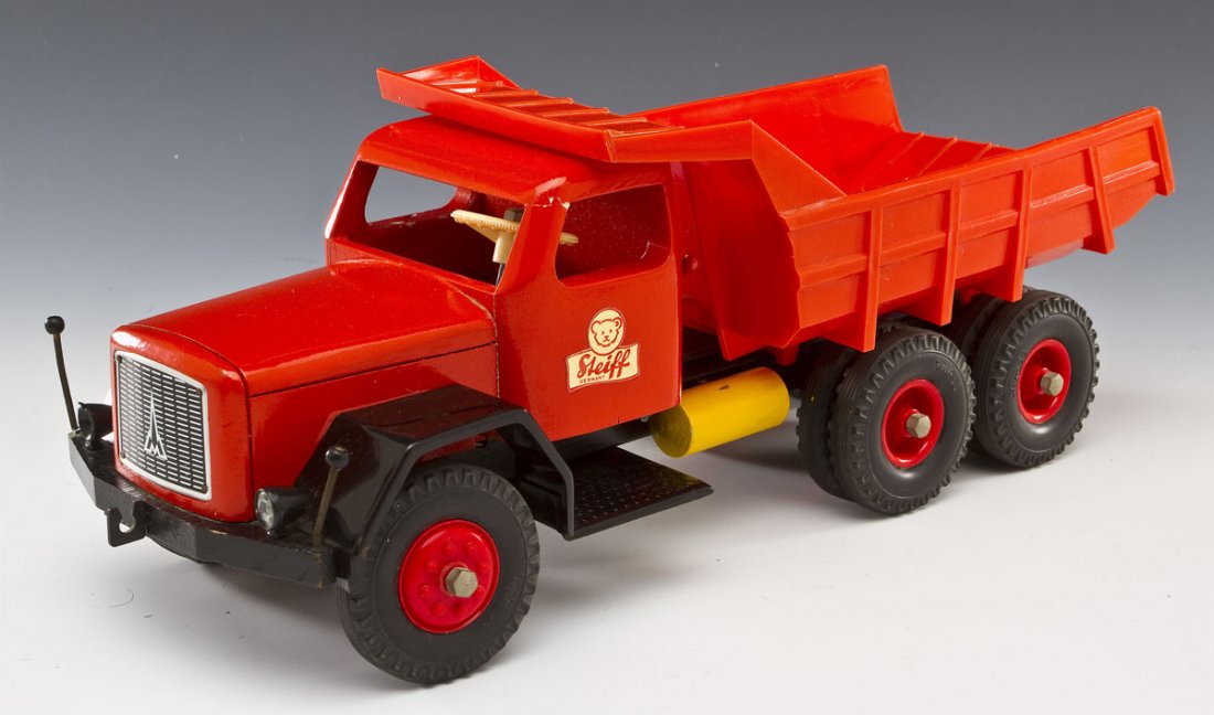 Steiff Red Dump Truck: DESCRIPTION: Steiff metal, wood and plastic dump truck in red. Labeled to sides of doors. MEASUREMENTS: 15" long. CONDITION: Minor paint chipping to passenger window frame. Top front of each window fr