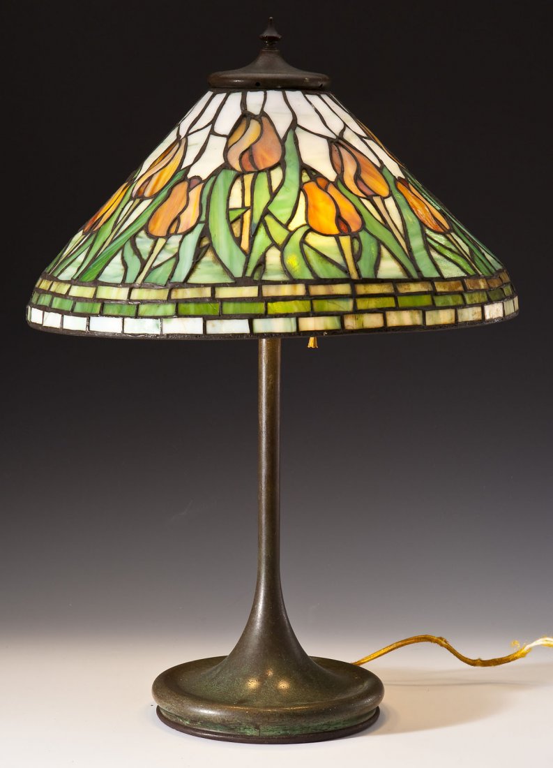 Leaded Glass Lamp with Tulips: DESCRIPTION: Leaded glass lamp with tulips on a white metal base with bronze finish. Base unmarked. MEASUREMENTS: 23-1/2" tall. 16-1/2" diameter of shade. CONDITION: Working. Minor wear to surface con