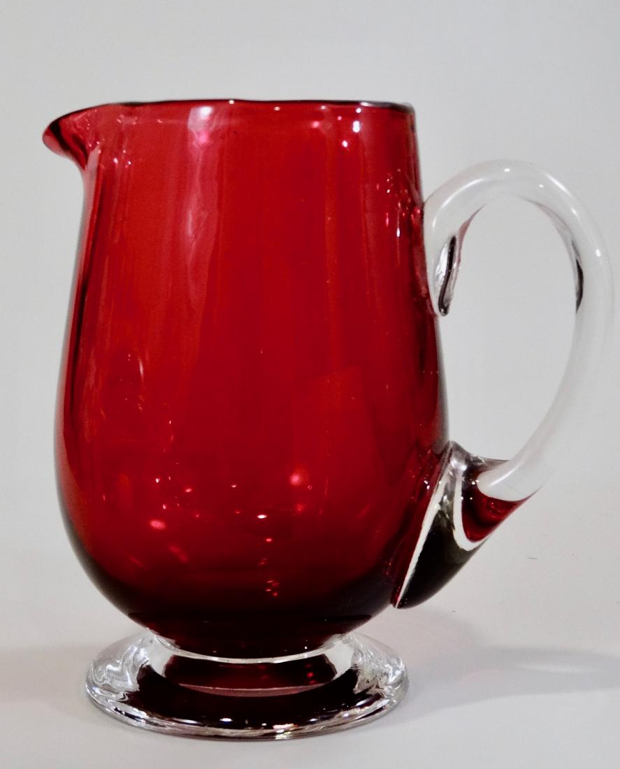 Vintage Footed Cranberry Studio Art Glass Cream Pitcher: Vintage Footed Cranberry Studio Art Glass Cream Pitcher Approximately 3 15/16 inches tall.