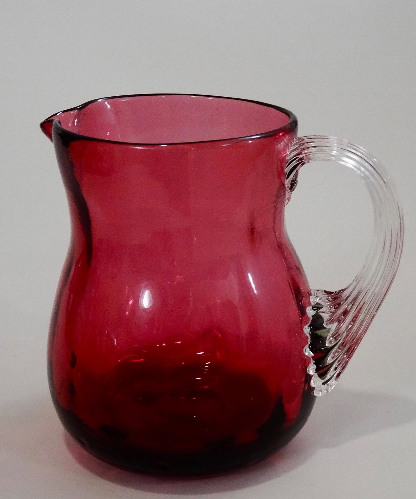 Pontil Blown Cranberry Art Glass Creamer Pitcher With: Pontil Blown Cranberry Art Glass Creamer Pitcher With Reeded Handle 3 7/16 inches tall.