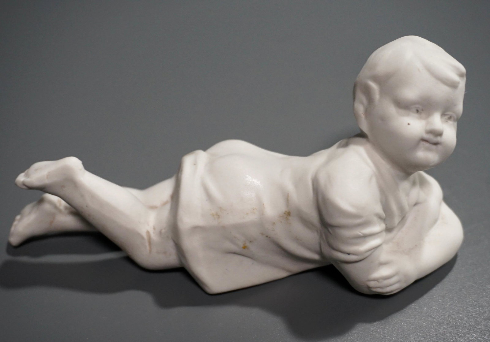 Antique Victorian Bisque Porcelain Boy Figurine: Antique Victorian Bisque Porcelain Figurine Reclining Boy Approximately 5 7/16 x 1 7/8 x 2 9/16 inches.