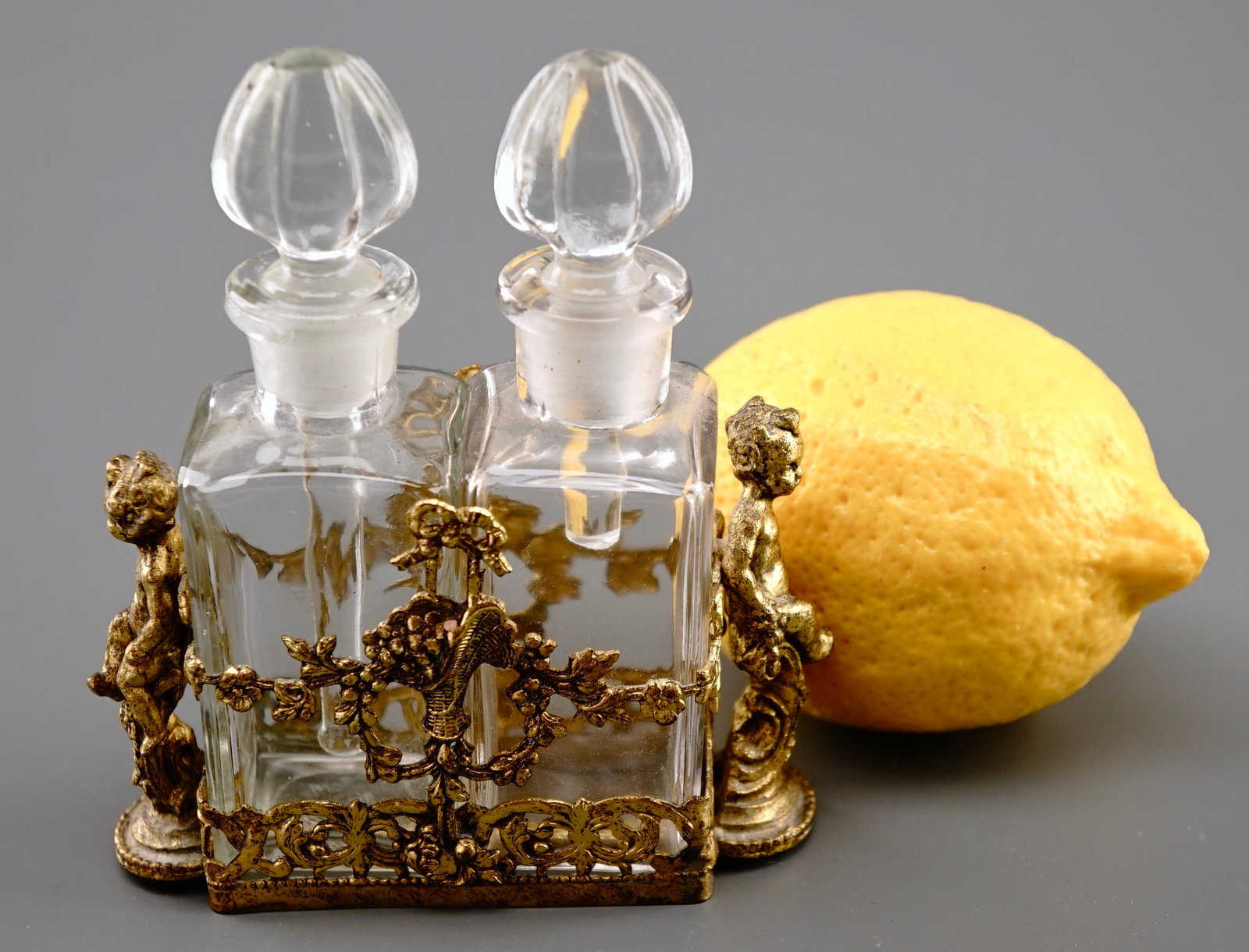 Ormolu Cherub Double Perfume Bottle Casket Holder: Ormolu Cherub Double Perfume Bottle Casket Holder Approximately 4 x 1 5/8 x 4 5/8 inches tall. Shipping Estimate:SHIPTHEBAY estimate for shipping of this lot in the Continental US is $20, which includ