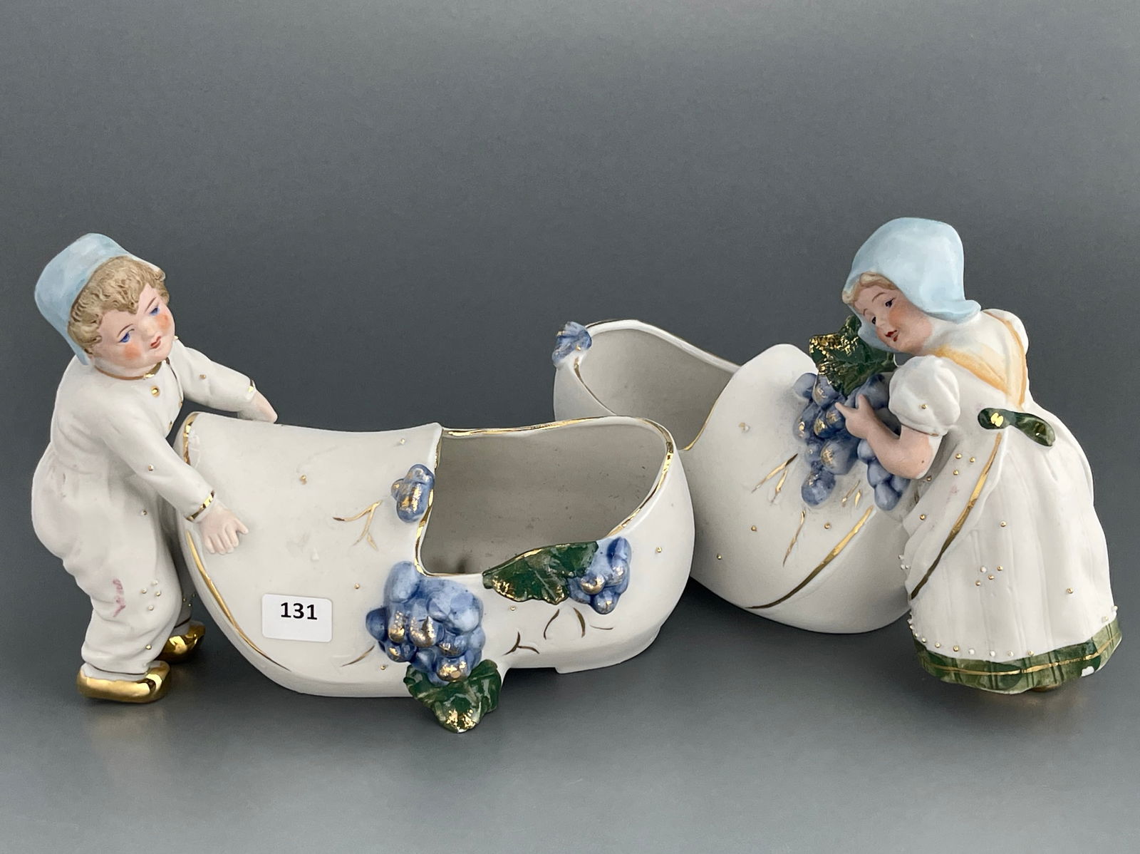 Pair of Antique German Small Figural Bisque Porcelain Planters Grapes Clog Vase with Dutch Children: Pair of Antique German Small Figural Bisque Porcelain Planters Grapes Clog Vase with Dutch Children Figurines c. First Quarter of 20th Century Approximately 7 1/2 x 3 x 5 1/4 inches tall.