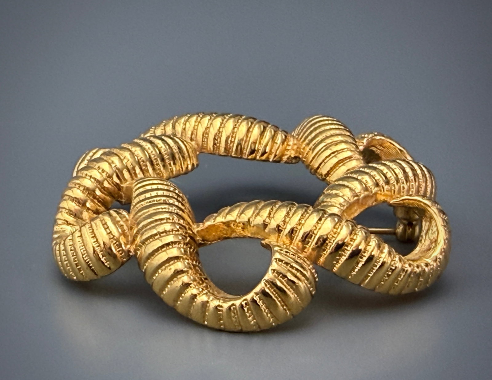 Monet Brooch Large Textured Ribbed Gold Tone Interlocking Swirl Wreath Vintage Signed Costume: Monet Brooch Large Textured Ribbed Gold Tone Interlocking Swirl Wreath Vintage Signed Costume Jewelry Approximately 2 3/8 inches in diameter.