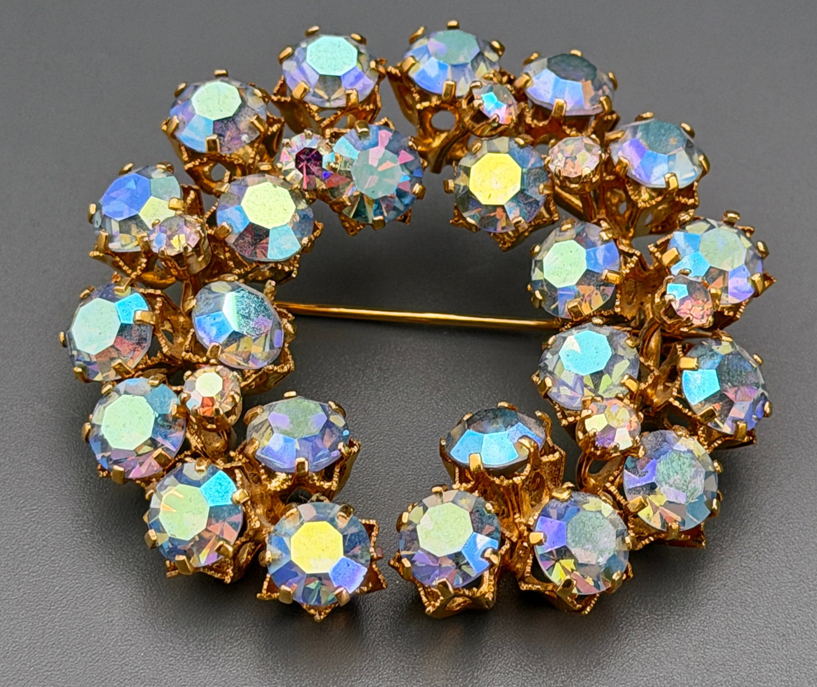 AUSTRIA Signed Gold Tone Aurora Borealis Rhinestone Open Wreath Brooch Pin Multi Tiered Crown Prong: Vintage AUSTRIA Signed Gold Tone Aurora Borealis Rhinestone Open Wreath Brooch Pin Multi Tiered Crown Prong Fashion Costume Jewelry Approximately 2 inches in diameter.