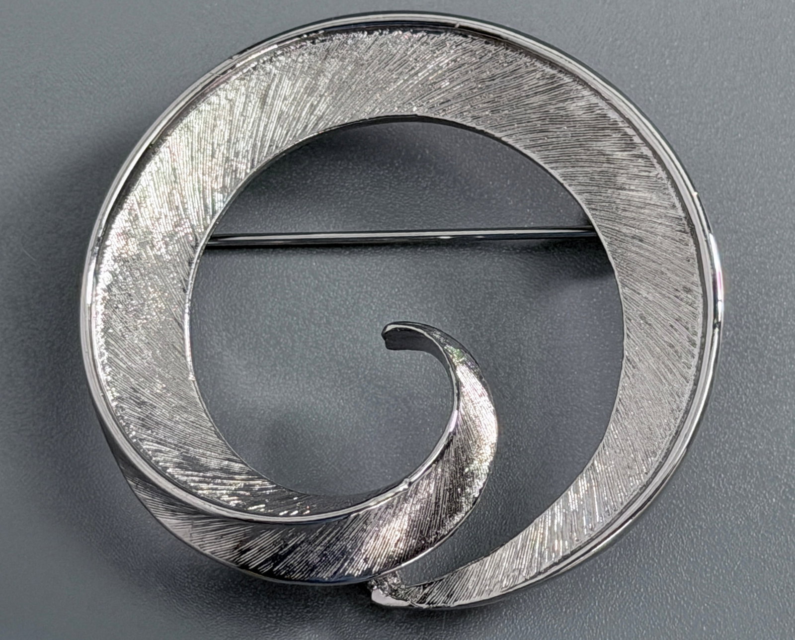 Vintage Silvertone Textured Swirl Open Circle Pin Brooch Wave Ribbon Spiral Minimalist Modernist: Vintage Silvertone Textured Swirl Open Circle Pin Brooch Wave Ribbon Spiral Minimalist Modernist Fashion Costume Jewelry Approximately 1 3/4 inches in diameter.