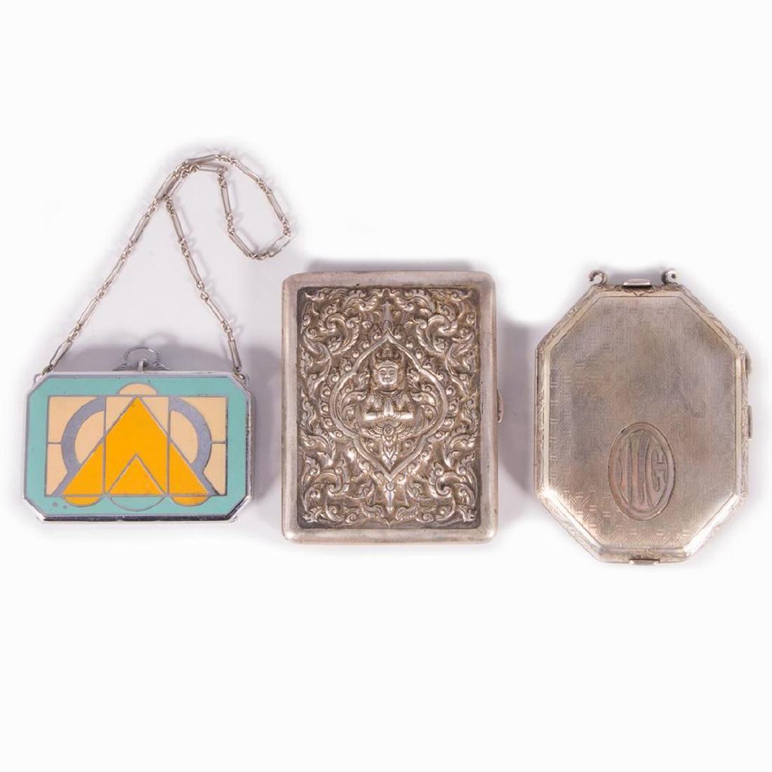 Three early 20th century compacts.: A 1920's sterling compact/case with an Indonesian motif measuring 3 inches high x 2 1.2 wide - approx 40 grams. An early 20th century sterling compact measuring 3 1/4 inches high x 2 1/2 wide - approx