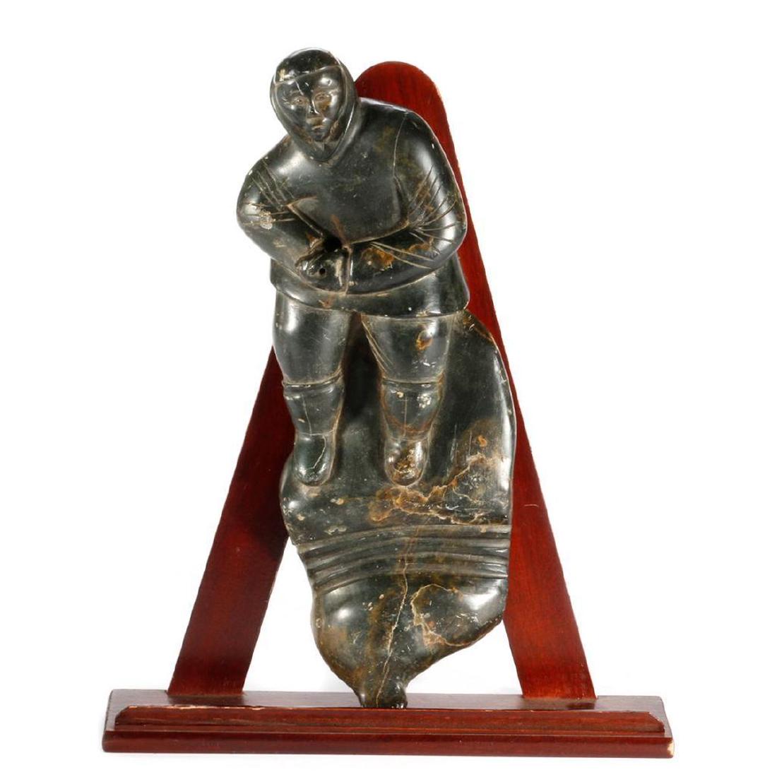An Inuit Stone Sculpture: Unidentified artist, "Hunter Pulling a Seal" Length: 13 1/2in