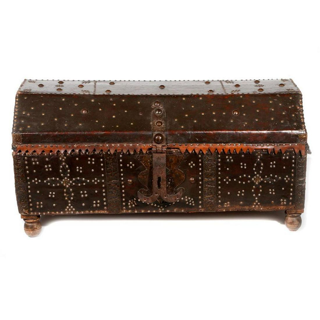 A Spanish Colonial trunk.: A 19th century Spanish Colonial domed leather covered trunk with tack detail and cast iron locks. One rear foot replaced and not attached. 22 inches high x 44 1/2 inches wide x 21 1/2 deep.