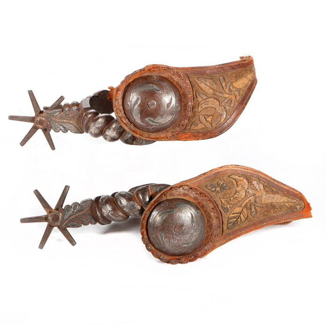 Pair of Mexican spurs: c. late 19th/early 20th century, with silver inlay decoration and pitado fiber embroidery Each 10 inches long x 5 wide.