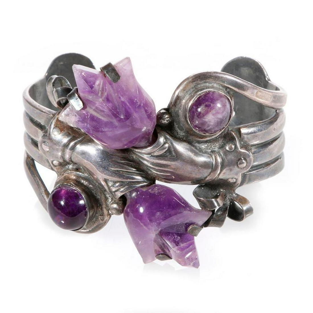 Mexican silver bracelet: c.. first half 20th century, a cuff, designed with crossed arms holding amethyst bouquets, stamped Mexico Sterling M. 2 inches high x 3 inches across. Weight: 90 g.