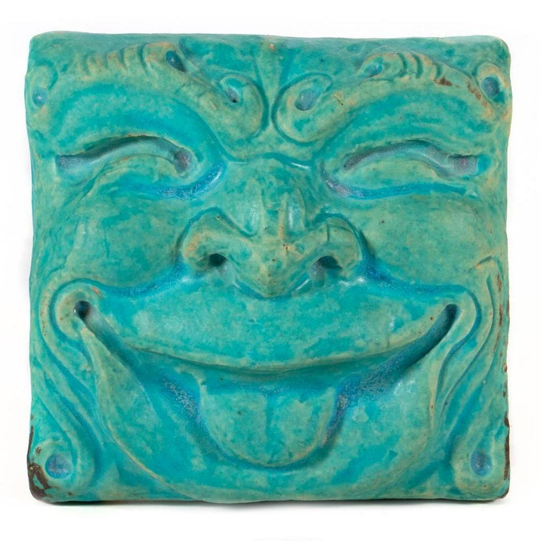 Pewabic Pottery Tile: In the form of a grinning grotesque. Incised Pewabic Detroit 1985. 6in. (15cm) square. Condition: Very good.