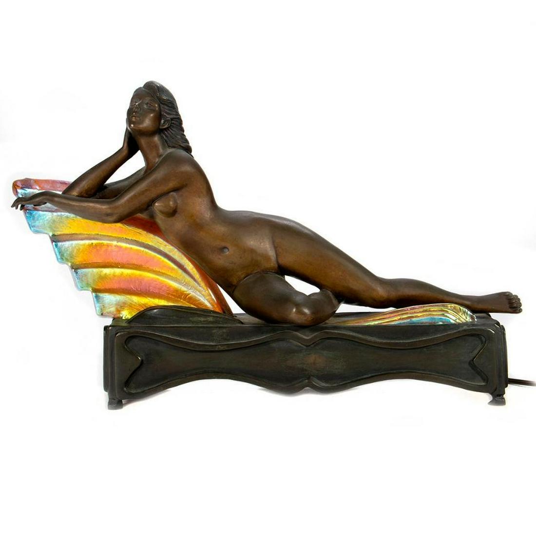Chiparus Art Deco Bronze Table Lamp: Cast as a reclining Female nude with iridescent glass waveform fixtures. 11in. (29cm) h. 17in. (43cm) l. Condition: Very good.