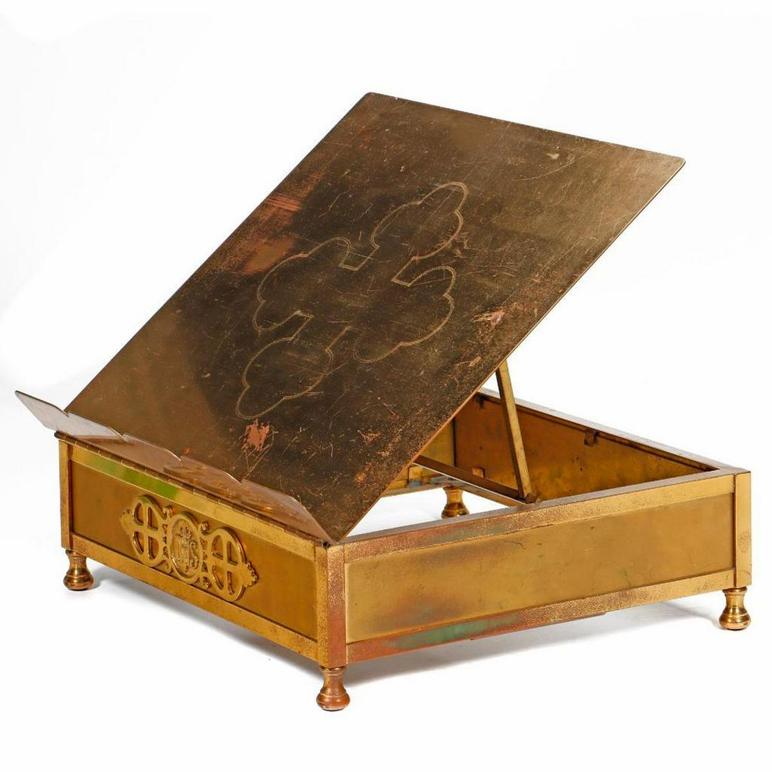 Brass Missal Stand with Trefoil Cross: The stand with "IHS" device on the front. 14 3/4in. w. x 12 3/4in. d. x 4 1/2in. h. Condition: The surface with scratches/wear, patina on sides.