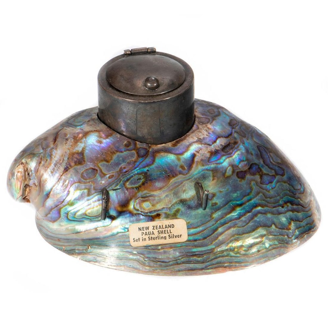 An Art Nouveau Sterling and Shell Inkwell: The sterling inkwell mounted on a New Zealand Paua shell base. 2 1/2in. (6cm) h. 5 1/2in. (14cm) l. Condition: Very good