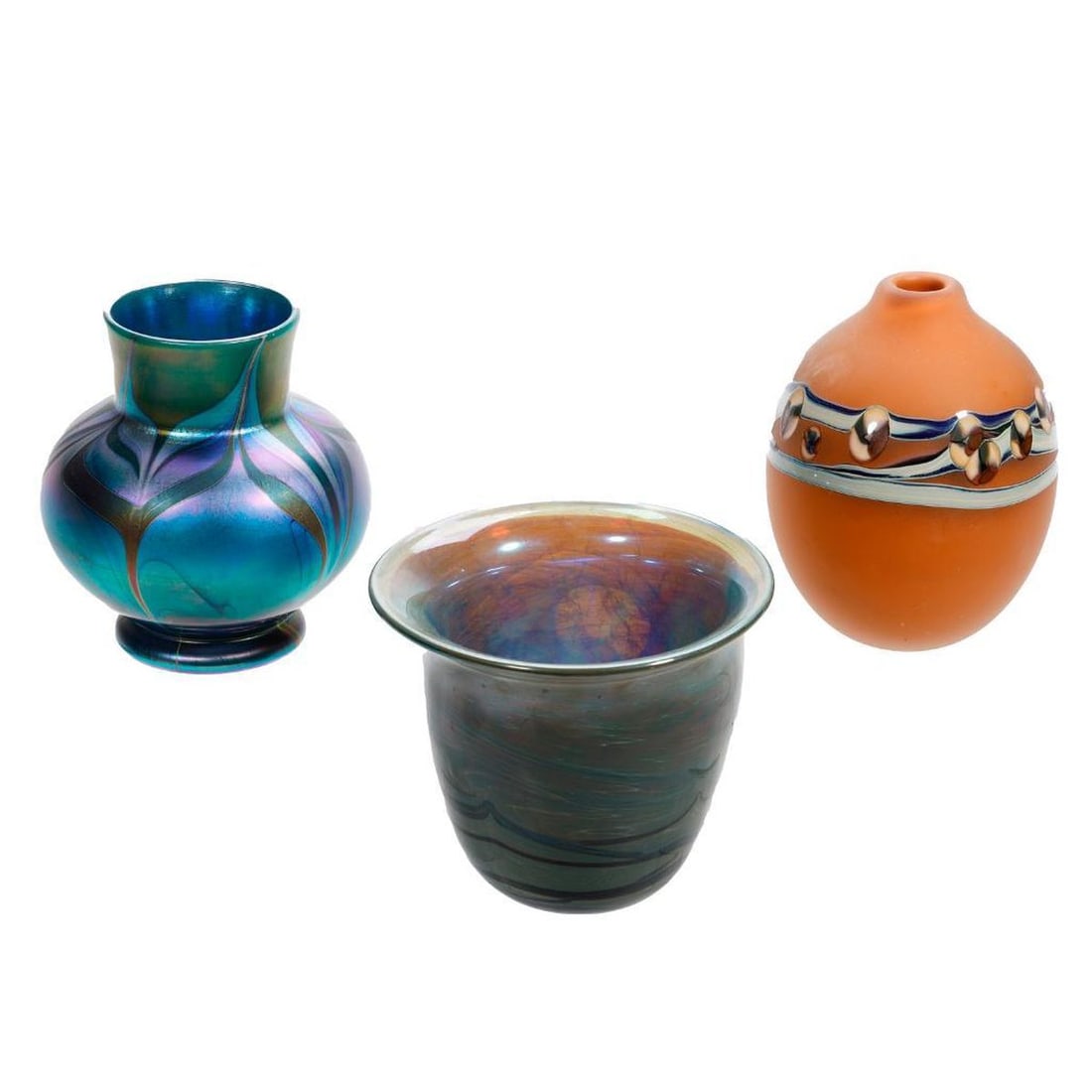 Three Contemporary Studio Art Glass Vases: (1) The first, a footed ovoid form in blue iridescent glass decorated with bronze and purple feather pull fashioned in the Tiffany style, etched signature scratched out, 5.5"h x 5"d mid body. (2) The