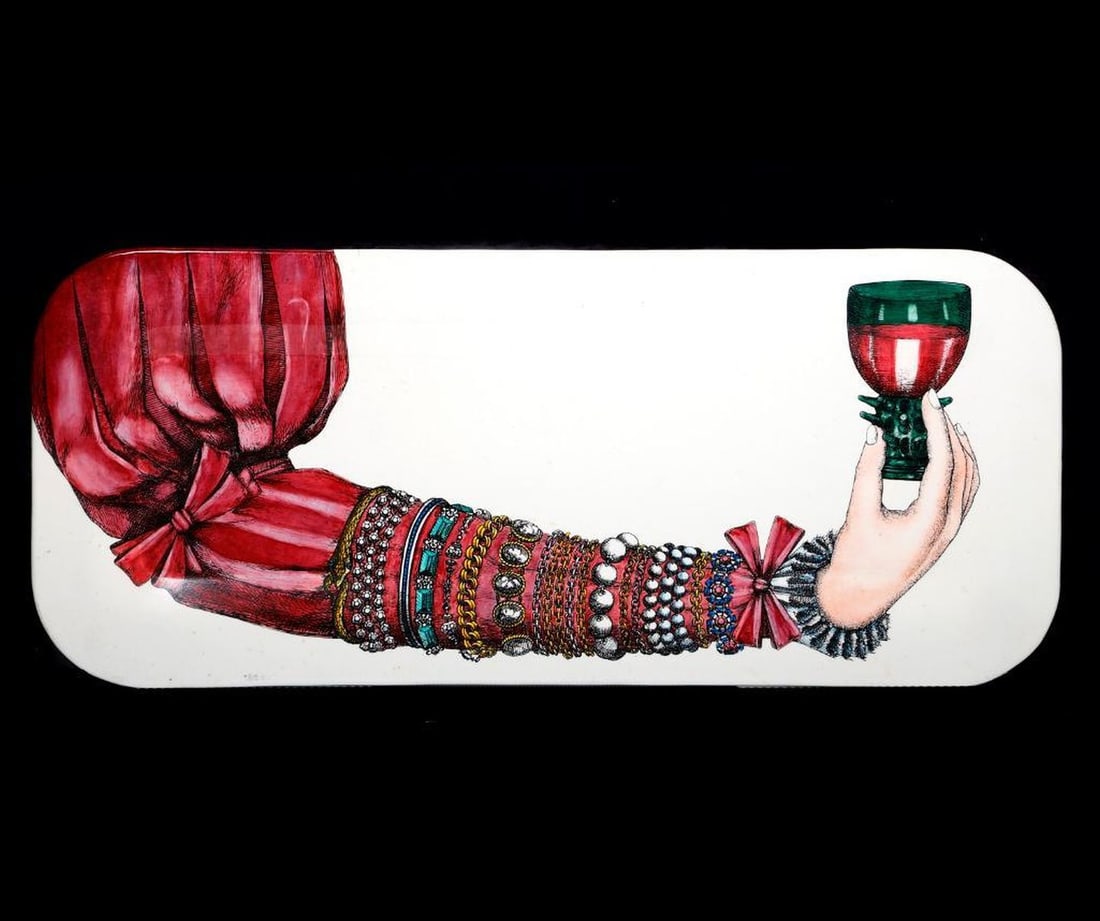 Fornasetti Jeweled Arm Metal Tray: A Piero Fornasetti (Fornasetti-Milano) enameled metal tray in Braccio Ingioiellato design, depicting a woman's sleeved and bejeweled arm holding a green cordial glass; on white background. Label on ba