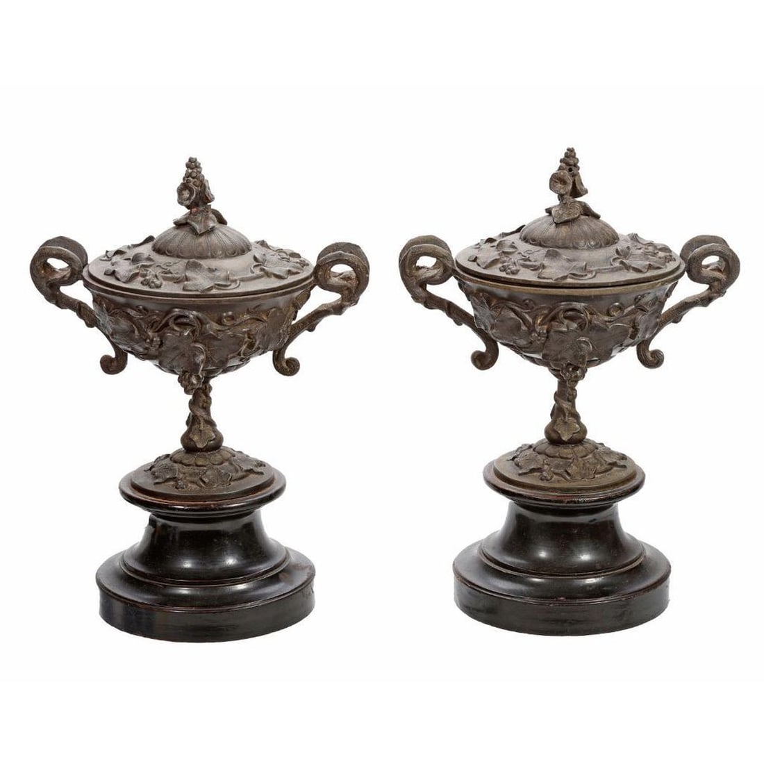 Pair Aesthetic Movement Metal Covered Urns: Each of hat form cast with leafy bunches of grapes, rising on a vasiform standard with an entwining leafy vine, the dish form lid cast with a trumpet flower handle, the whole on ebonized wood socle ba