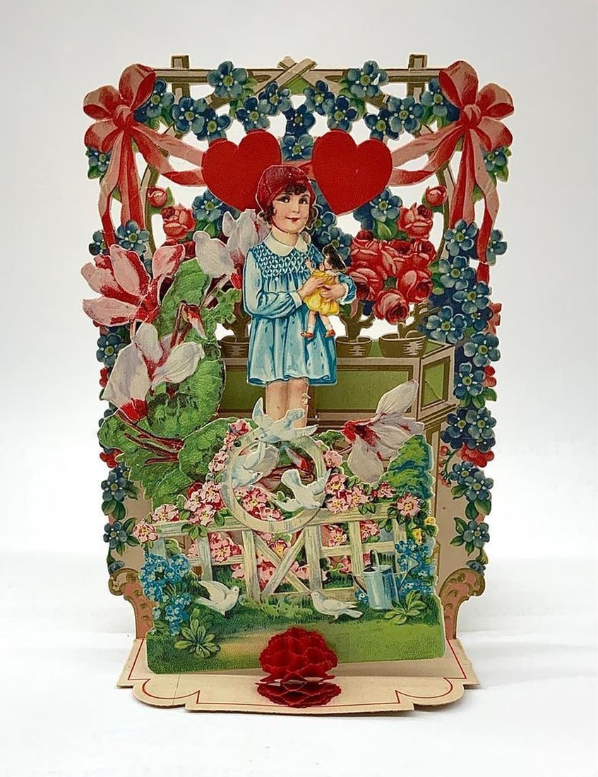 Valentine Card: pop-up with girl in flower garden: Pop-up Valentine with color illustration of standing young girl holding a doll in a middle of a flower garden, small red honeycomb ball in foreground, two hearts hanging in the background. Medium: