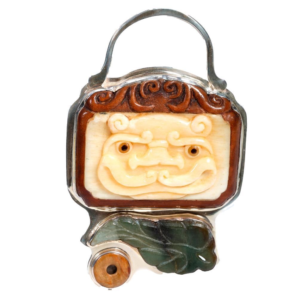A stone and sterling silver slide pendant: with carved bone, wood and jade, depicting an animal face and leaf; engraved 'gg'; measuring 4 1/2 x 2 3/4 in.; weighing approximately 81.5 grams