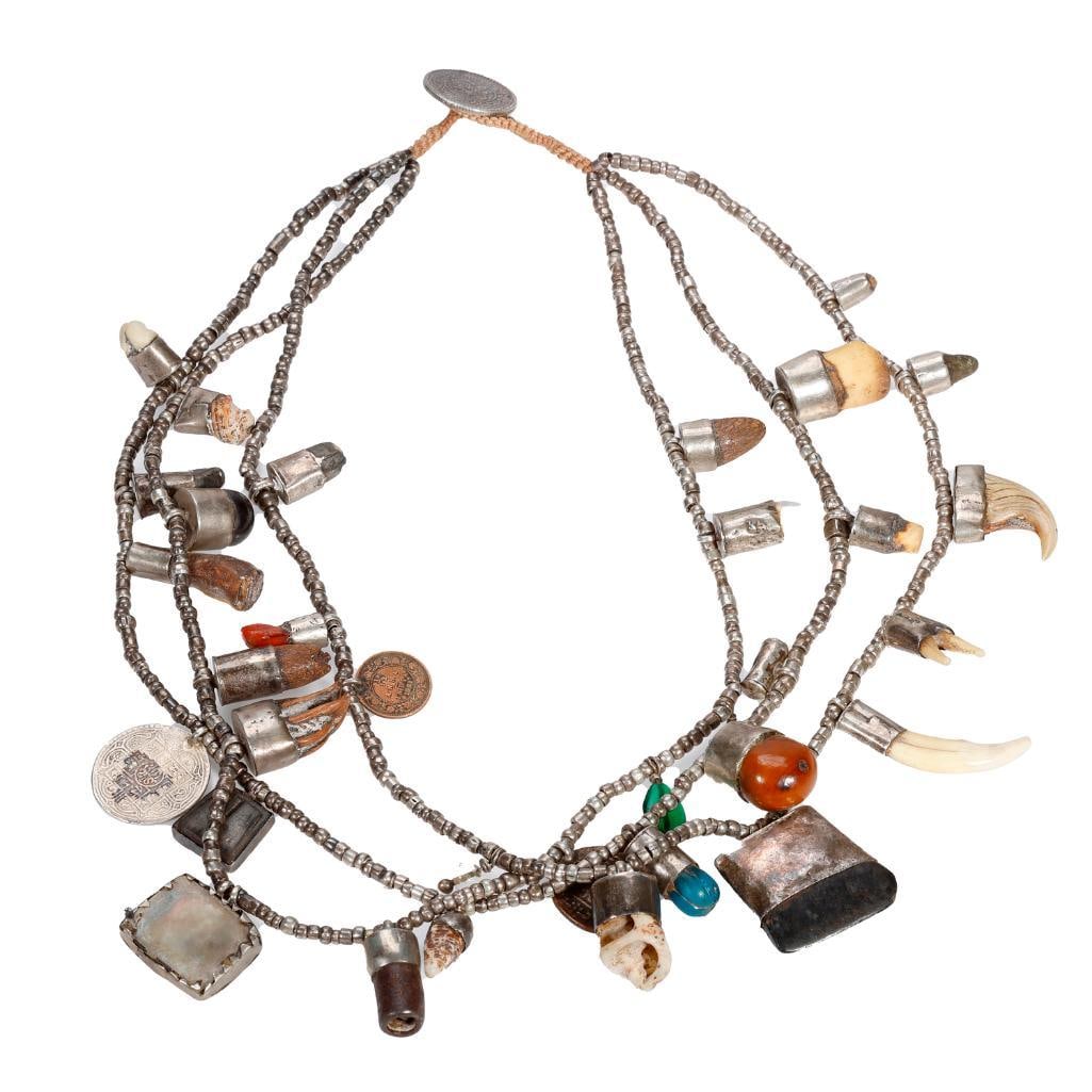 A triple strand fetish necklace: in silver and metal, with animal claws, teeth, shell, stones and coins