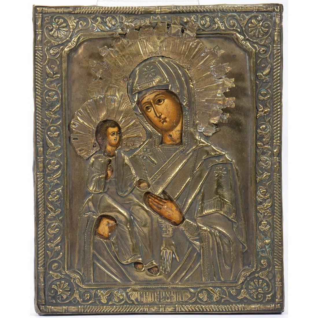 Copper Oklad Painted Icon of Madonna: The figures having painted faces/hands, with nail-attached halos, surrounded by a scrolling leaf border. 8 3/4in. x 7in. Condition: Overall good; scratches and wear to paint, losses to border of