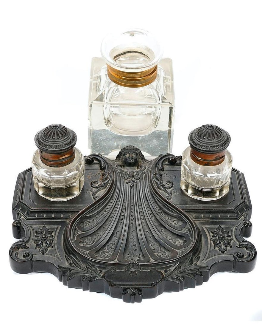 Ebonized Inkstand, and Large Ink Bottle.: The ornate inkstand with two fitted hinged-lid ink bottles, the stand 7 1/2in x 9in. Together with a large glass ink bottle, 5in x 3 1/2in x 3 1/2in (small hole in top, possibly from missing finial).
