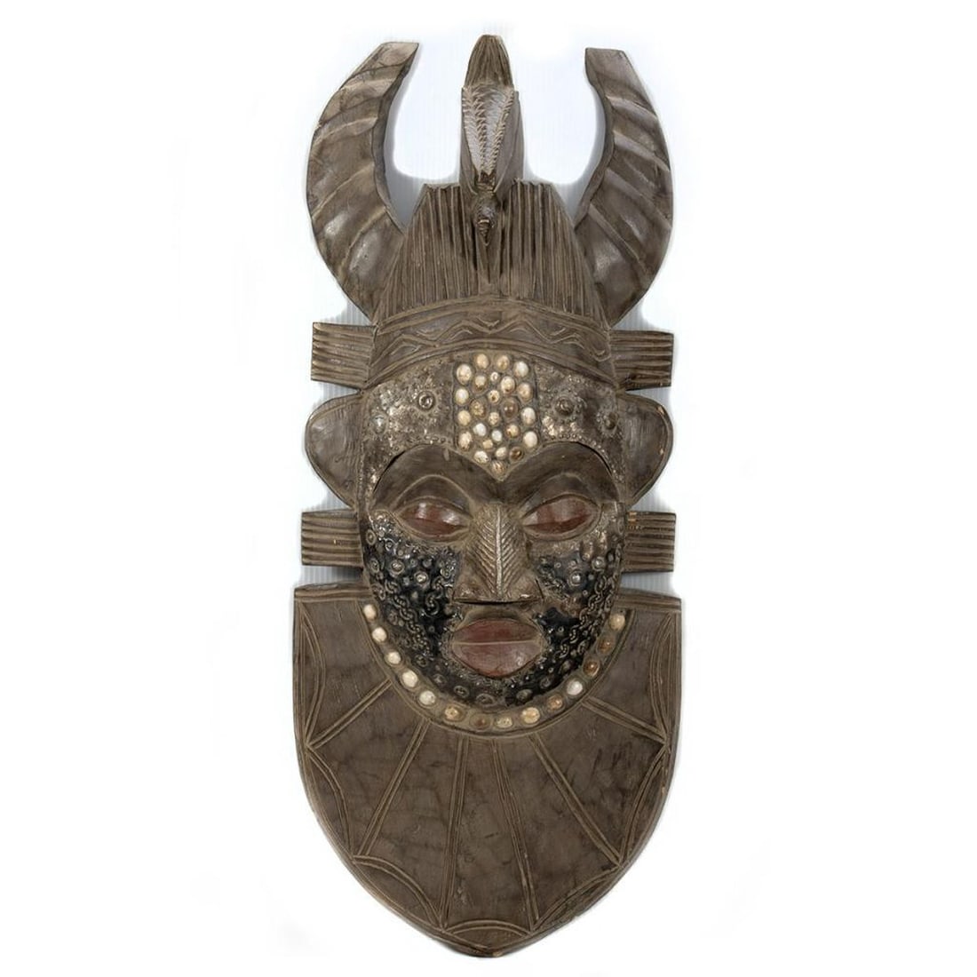 Ashanti Mask, Ghana, 20th Century: The carved wood mask with a horned headdress, inset shells, and hammered/stamped metal embellishments. 30" x 12 1/2". Condition: overall good, some small chips/scratches to wood.