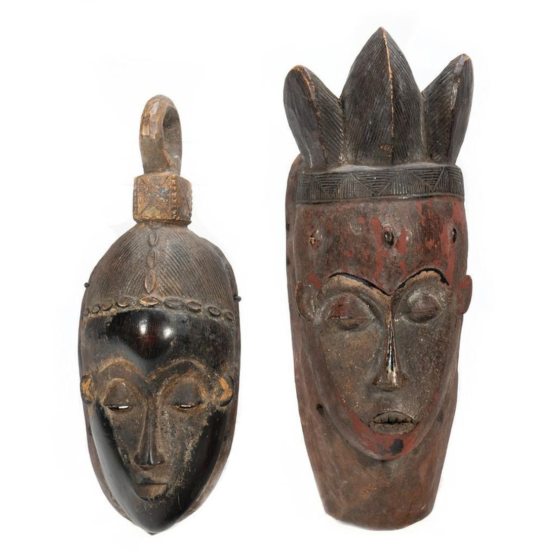 2 Guro Ivory Coast Carved Patinated Wood Masks: The first pre-1950s mask with a three-part headdress, jagged teeth, and black and red patination; 15" x 5 1/2"; color is worn/chipped; an old break on one edge. The second with dark patination an