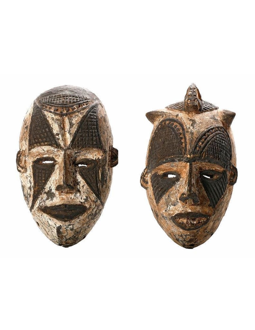 Two Nigerian Tribal Spirit Masks: Two carved wood tribal spirit masks of a male and female, both with white and black pigments, pierced eyes, and holes around the perimeters. Approx. 10 1/2" and 10" in length. Condition: both with wea