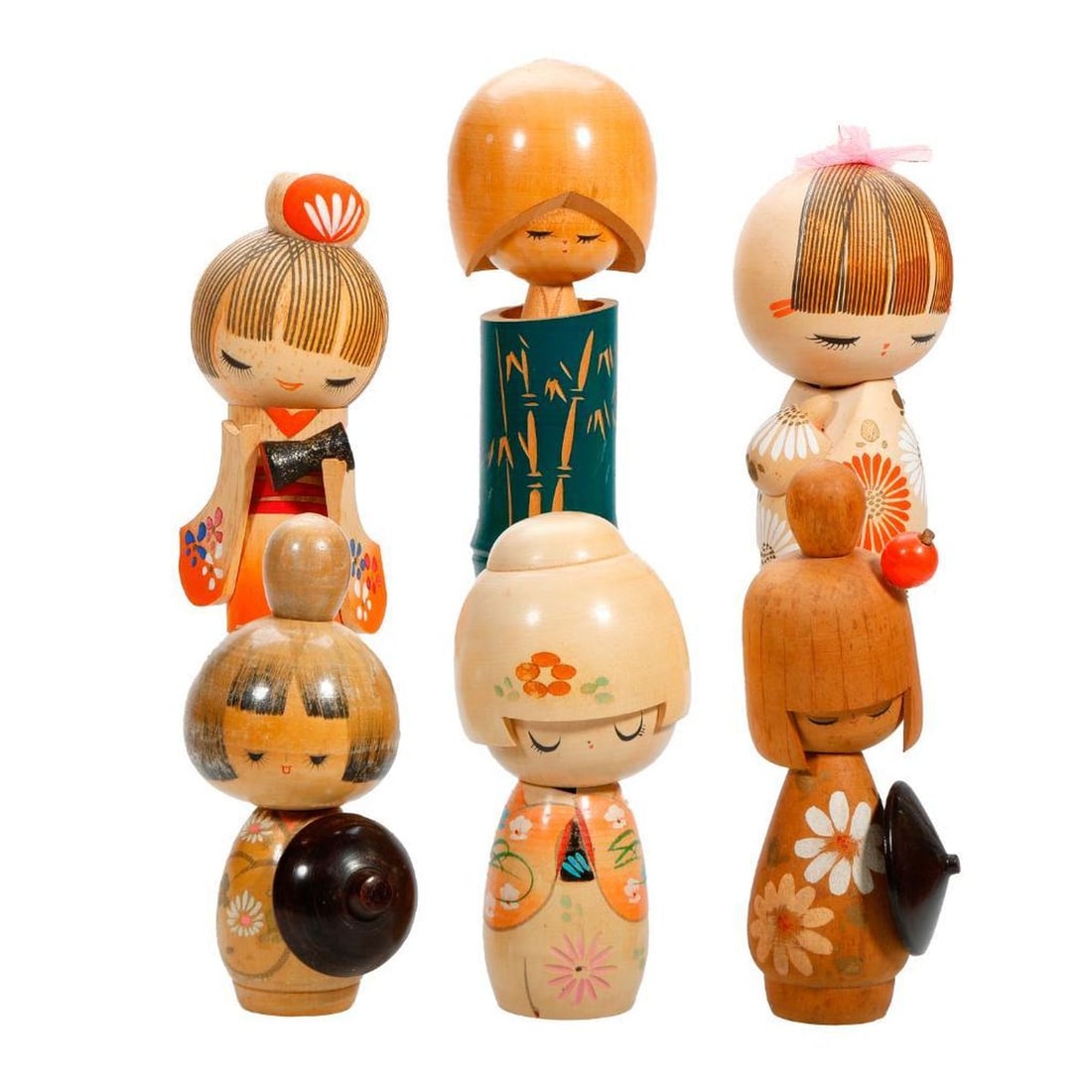 Six Japanese Kokeshi Blond Wood Dolls: Comprising five dolls wearing a kimono painted with flowers and having an applied "helmet" of bowl cut hair, the sixth, a souvenir doll with lithographed scenes of Osaka Castle, heights range fro
