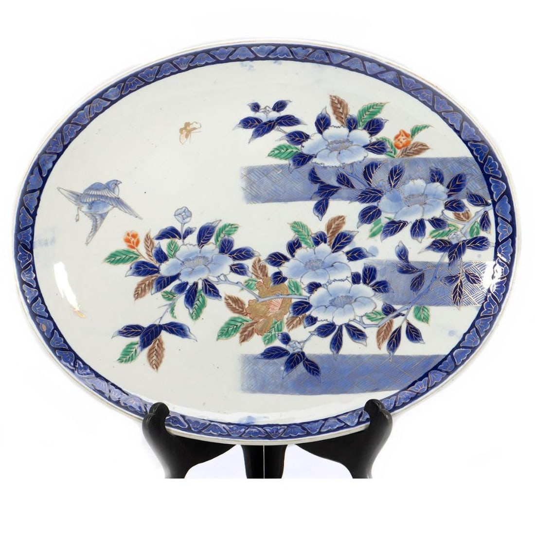 Large Oval Japanese Charger: Polychrome gilt floral decoration with a bird and butterflies, and gilt blue border. Mark on bottom. 24" x 19 1/2" x 3". Condition: No cracks or chips; wear to gilt rim.