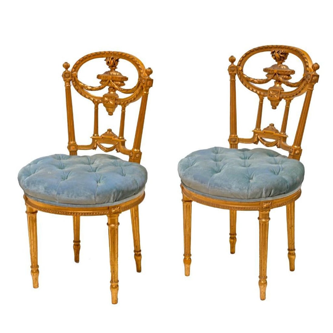 Pair Louis XVI Style Giltwood Salon Chairs: Each oval back centering a carved burning urn form oil lamp joined by a laurel leaf swag, on fluted stiles, over a tufted powder blue velvet upholstered auricular shaped seat rising on fluted legs,
