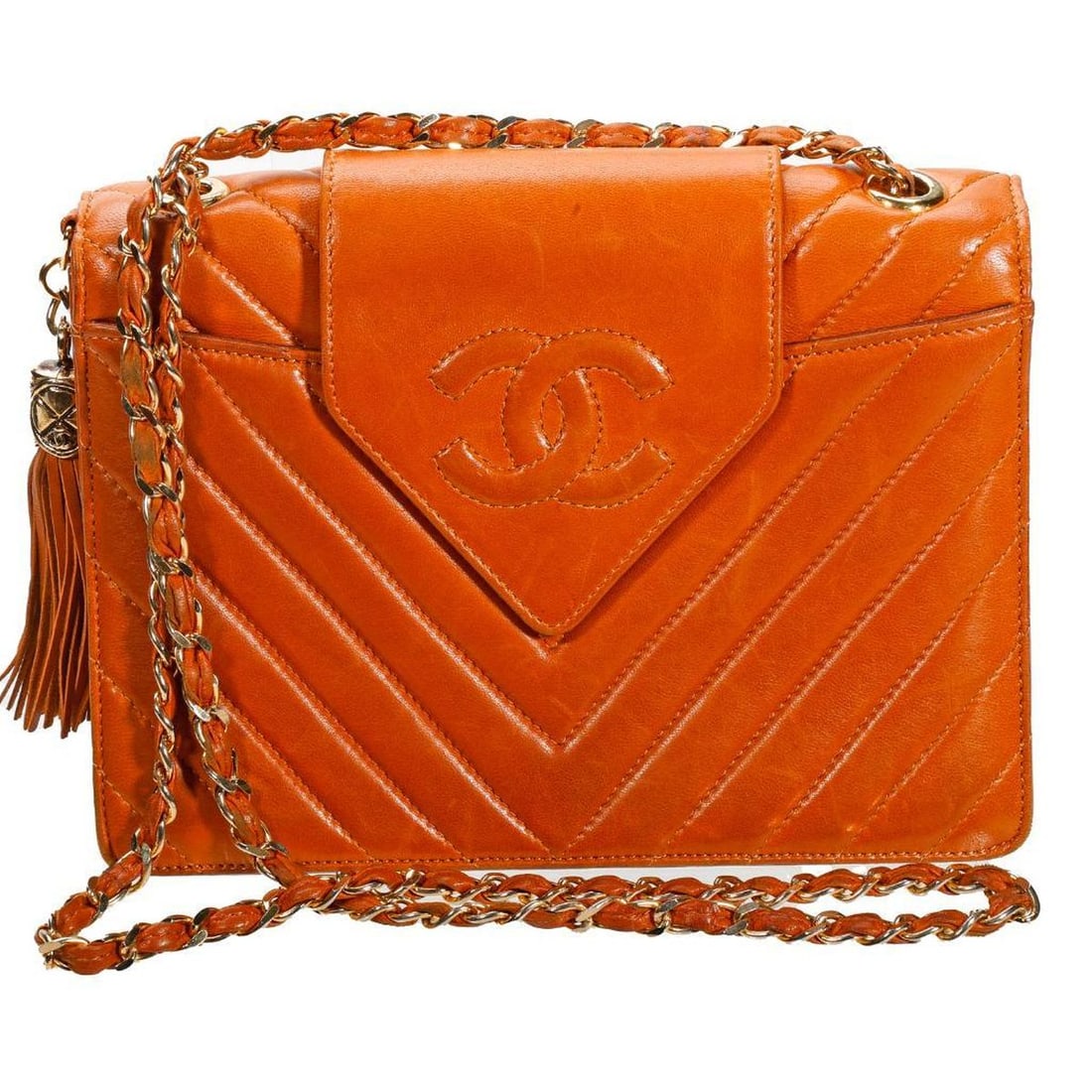 Vintage Chanel Chevron Stitch Purse: The circa 1989-1991 Chanel light brown lambskin purse with triangular snap flap with stitched CC, over chevron-stitched flap closure; a gold-toned metal/tassel side embellishment, and gold-toned metal