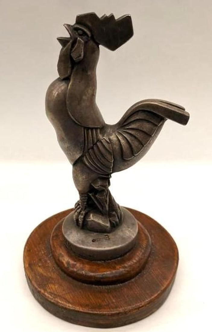 French Rooster Silvered Bronze Hood Ornament: Circa 1930, the radiator cap mascot finial of a rooster, mounted on a round, wooden pedestal with the inscription, "Chantecler du cocq sur sockle argenite" on the base of the bronze rooster, and "Depo
