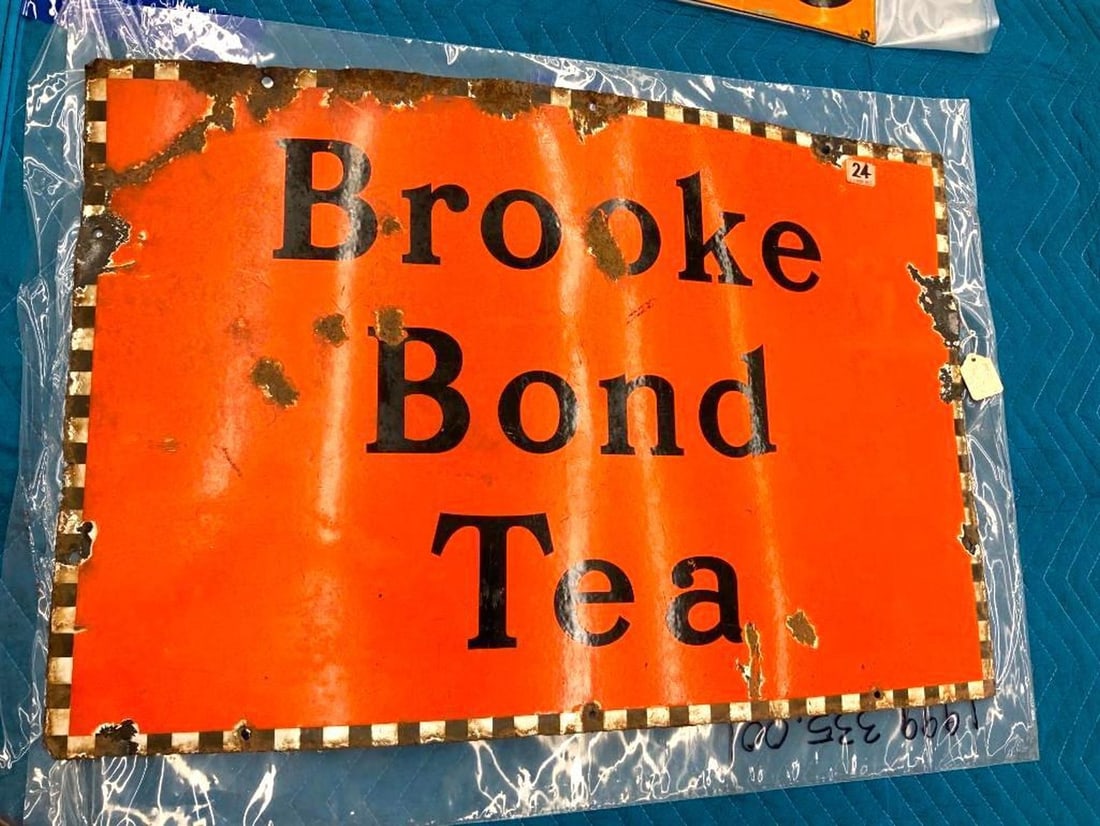 English Brooke Bond Tea Advertising Enameled Metal Sign: Circa 1930, the orange enameled metal rectangular sign with black lettering. Dimensions: 20" x 30" (50.8 x 76.2 cm) Overall fair condition, The sign is bowed. Some enamel loss and rust to the front an