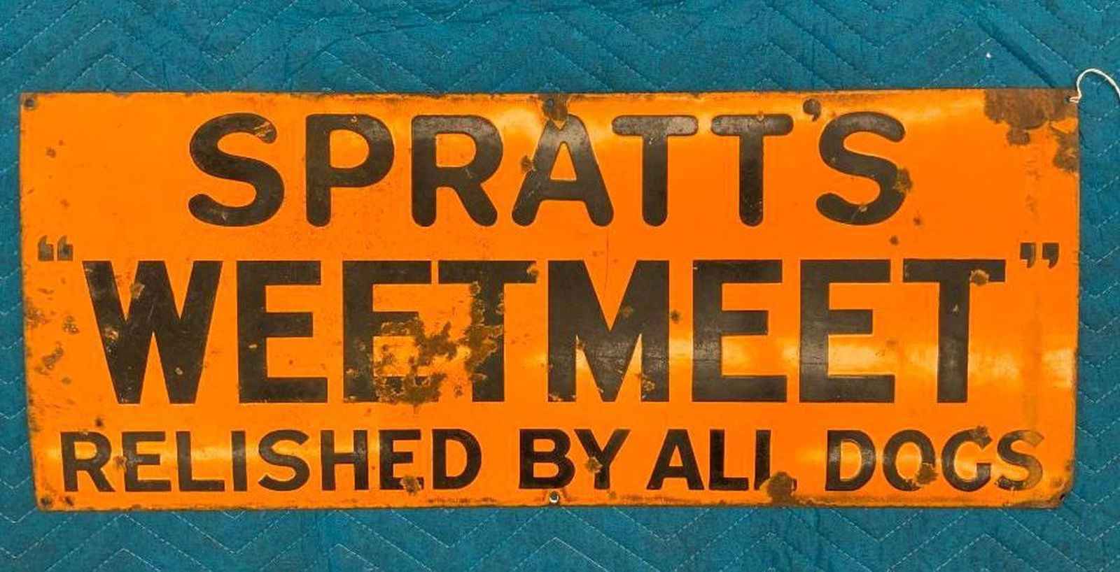 Spratts Weetmeet Advertising Sign: Circa 1930, the orange enameled metal sign reading "SPRATTS WEETMEET"/RELISHED BY ALL DOGS in black lettering.Dimensions: 12" x 30" x .25" (30.5 x 76.2 x . 6 cm) Overall fair condition, Some rusted/co