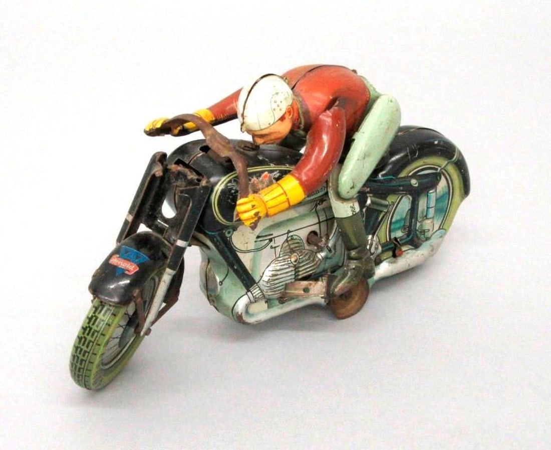 Arnold Mac 700 Tinplate Motorcycle and Driver: Circa 1940s, this tinplate clockwork motorcycle with driver; Arnold logo on front fender and "Arnold" printed on wheels; "Mac 700" decal on proper right side of fuel tank. Medium: metal, paint. Dimens