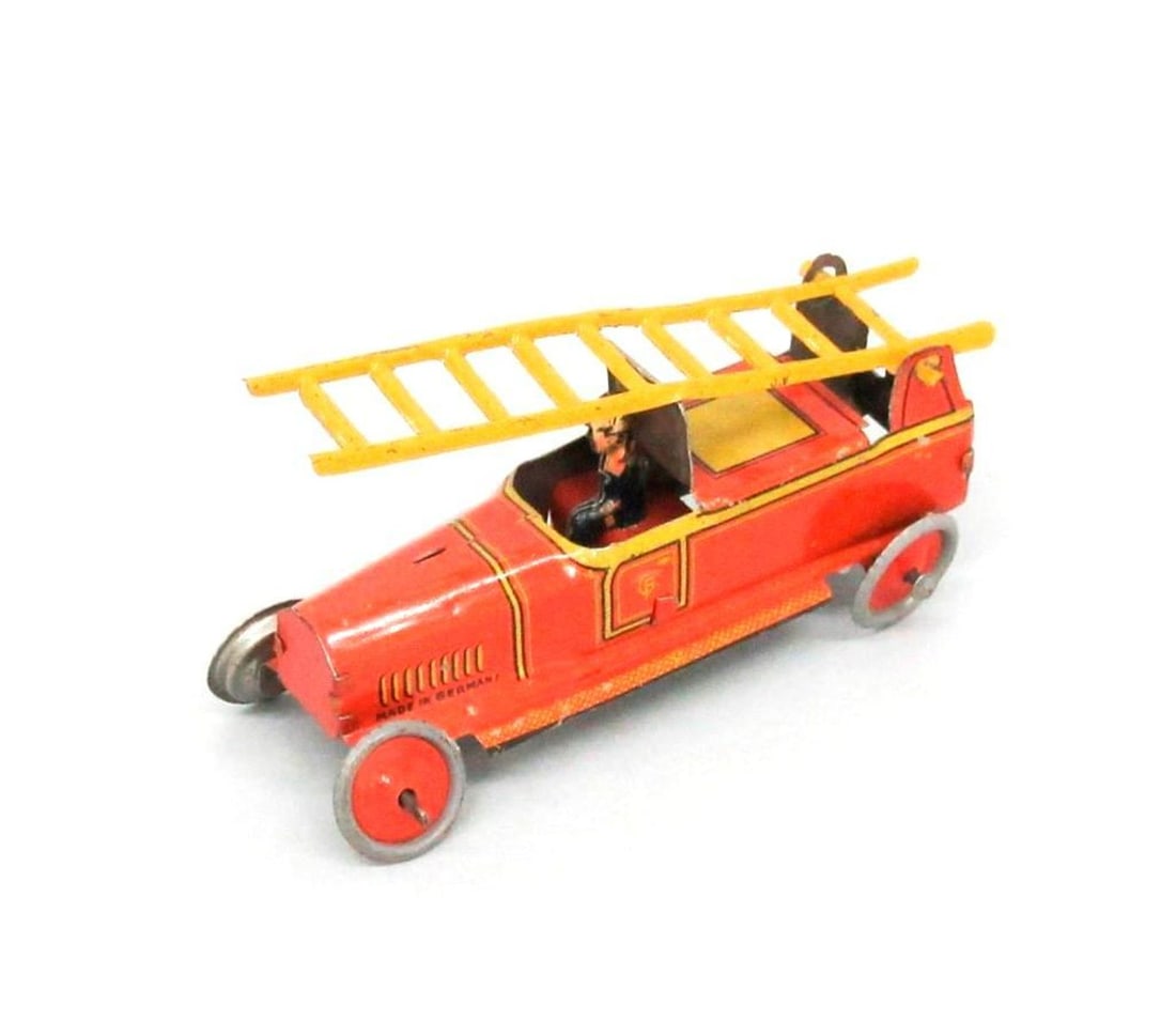 toy: Fischer, fire truck with ladder: Circa 1930s, the red fire truck having an articulated yellow ladder and a seated driver; Fischer maker's mark on exterior sides. Dimensions: 1.25" x .75" x 2.75" (3.2 x 1.9 x 7 cm). Condition: Abrasio