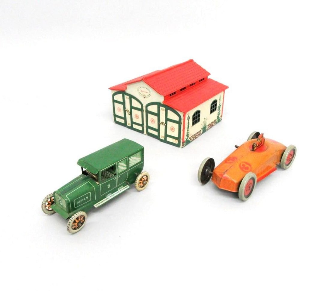 Lehmann Tinplate Garage and Two Cars: Circa 1934-1941, comprising a white tinplate garage with red roof; "772" / Marked "Lehmann" on back, 4.25" x 12" x 6.25"; an orange Lehmann Galop race car with "3" on hood; and a Lehmann green "Sedan"