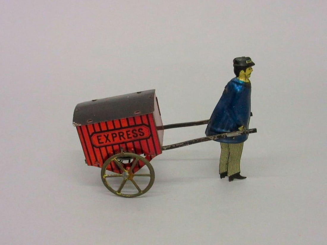 Lehmann Litho Tin Mechanical Express Cart" #770: Circa 1930s, the lithographed tinplate mechanical toy figure pulling a small red cart. Dimensions: 5.5" x 6.25" x 2.75" inches (14 x 15.9 x 7 cm). Condition: Figure's face on Pl side is bent. Missing