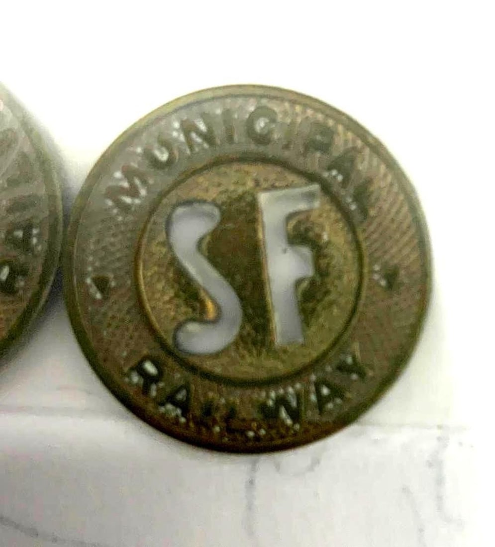 Two San Francisco Municipal Railway Tokens: Each bronze colored, "SF" cut away from center, taped to paper with address and phone number of Don Haywood. Dimensions: .75 inch dia. (1.9 cm dia.)