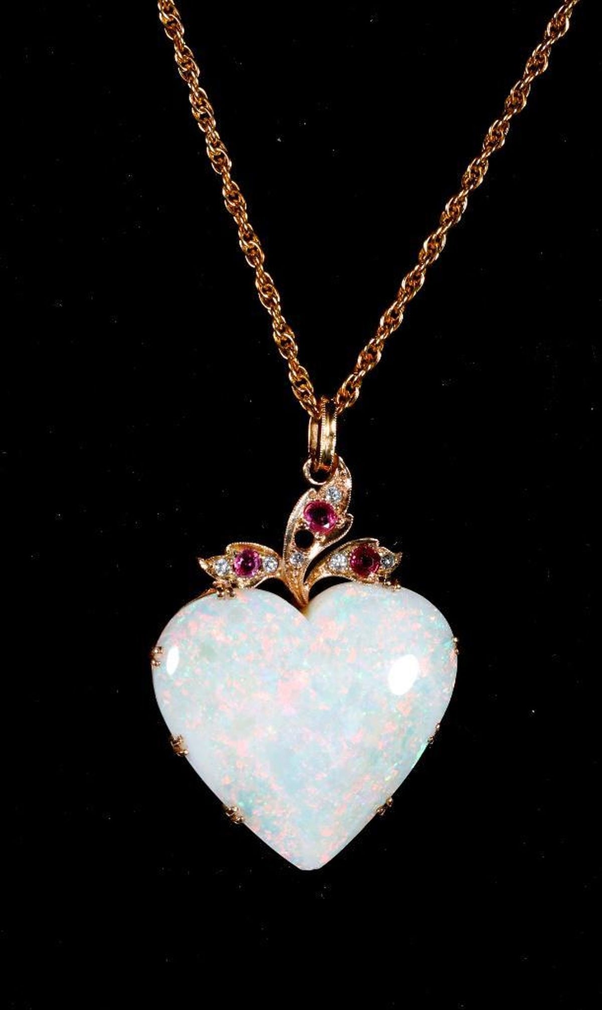 An opal, gem-set and 14k gold pendant and chain: centering a heart-shaped opal cabochon measuring approximately 30.0 x 28.0 x 8.90mm, accented by six round brilliant-cut diamonds and three round rubies; weighing approximately 16.6 grams; pendant len