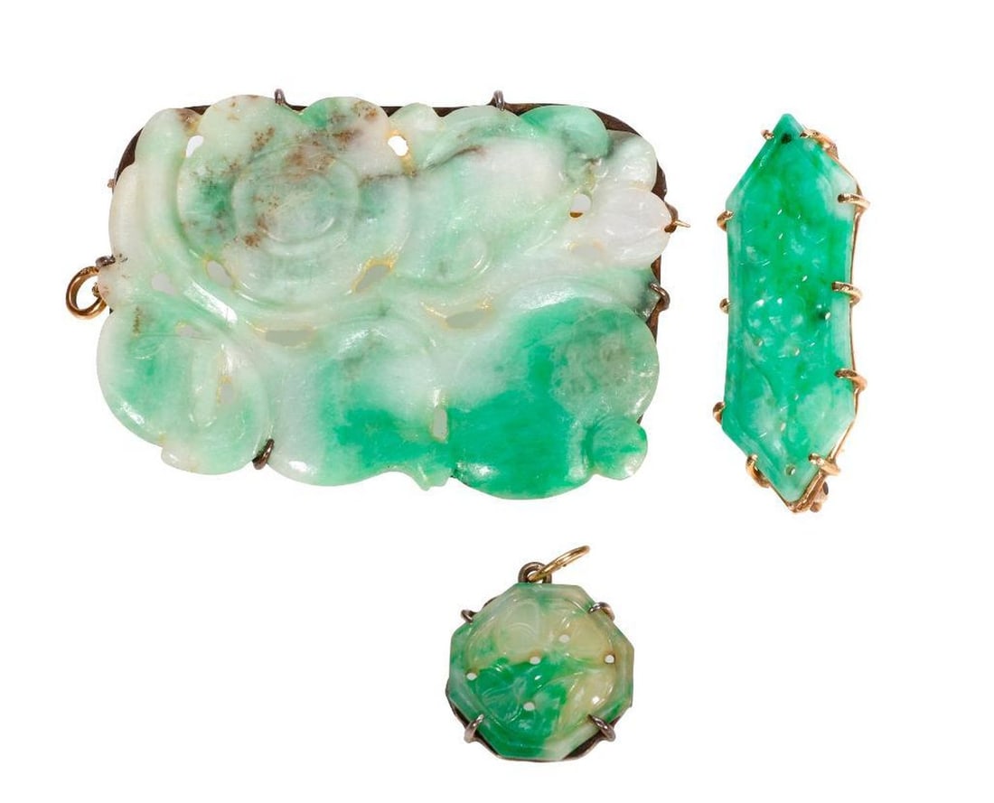 Three jade brooches/pendants: carved with foliate, floral and fruit motifs, comprising one elongated hexagonal jade set in 14k gold, an octagonal jade pendant set in silver, and a rectangular jade brooch/pendant set in silver ad g
