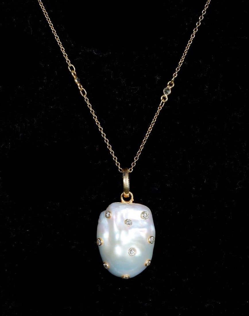 A cultured pearl, diamond and gilt silver pendant-necklace: the ornament featuring a freeform cultured pearl measuring approximately 22.50 x 17.0mm, dotted with bezel-set round brilliant-cut diamonds, completed by a diamond-set chain; length: 18-20 in.
