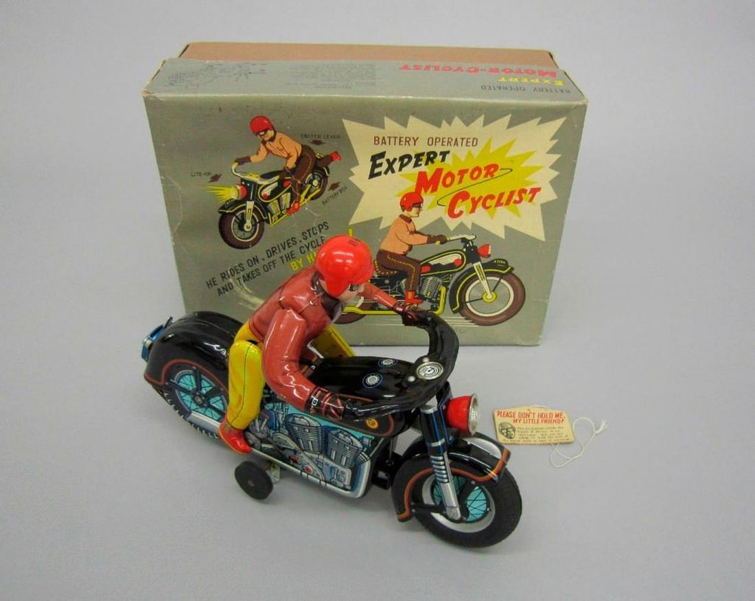 Boxed Japanese Modern Toys Motorcycle and Rider: Circa 1950s. Battery powered motorcycle with rider (Masudaya Atom). The body lithographed with engine details, fitted with rubber tires, headlamp. Original card stock box Patent No. 43276. 5.25"h x