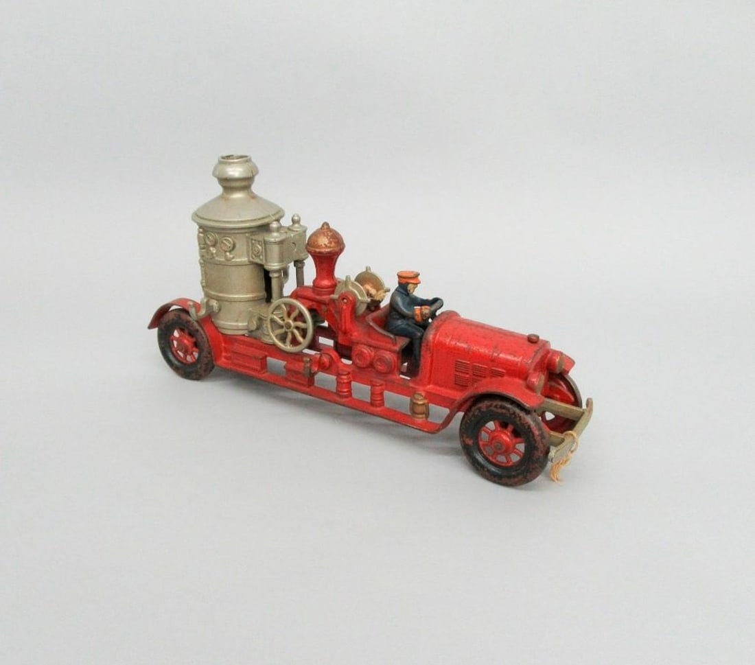 Kenton Toy fire truck: Painted and nickel-plated cast iron toy fire truck with original driver wearing blue outfit with orange hat and mittens. Dimensions: 7.75" x 3.75" x 14.75" (19.7 x 9.5 x 37.5 cm). condition: Mis