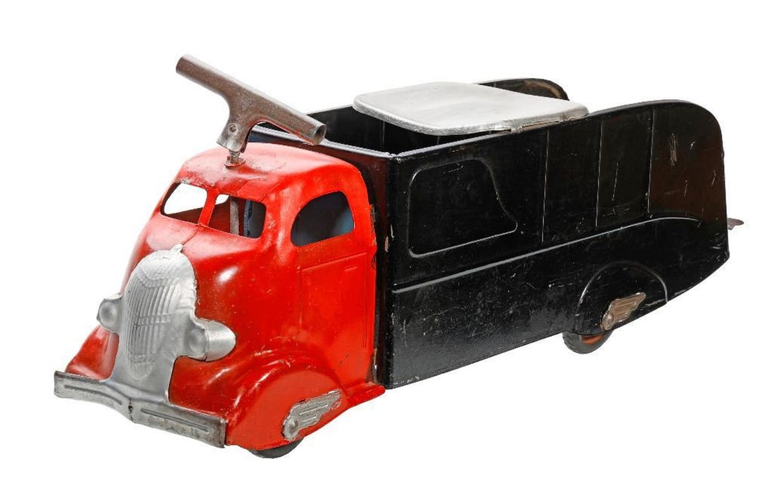 Vintage Rideable Toy Truck: Possibly Marx, a pressed steel truck painted with a red cab and black trailer body, having a handle/steering wheel in front and chrome seat over trailer, wheel covers with chrome fins, 11"h x 26"w x