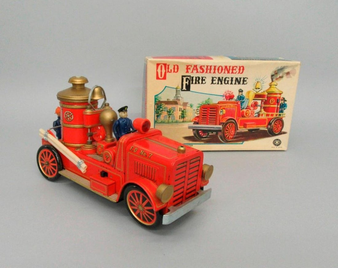 Modern Toys Fire Engine Truck with original box: Circa 1950. Battery operated toy fire engine with driver and fireman and original illustrated box. Dimensions: 5 x 13 x 8 inches (12.7 x 33 x 20.3 cm). Condition: Left side rail is loose, Tires worn f
