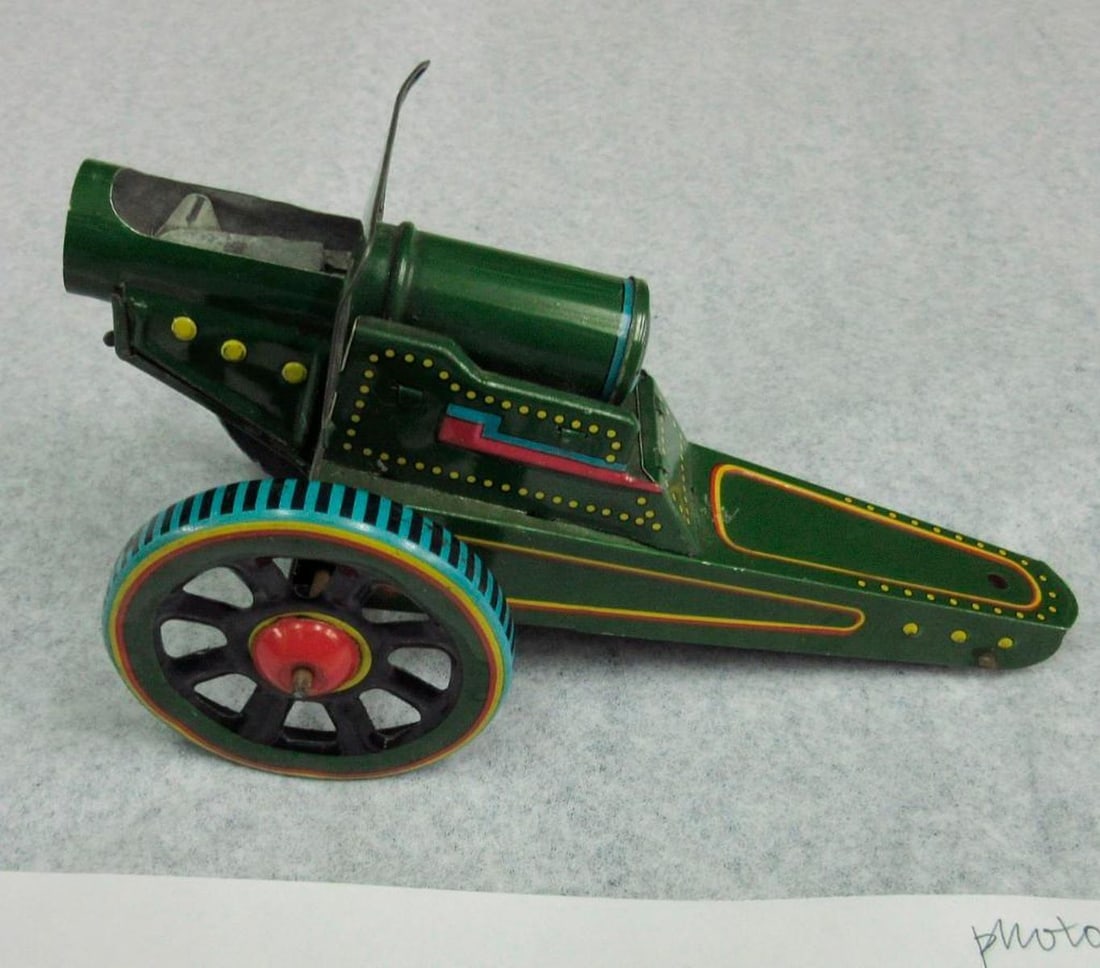 Chinese Tinplate Cannon No.279: Green tinplate toy cannon with Chinese characters decal and "No. 279 / Hong Kong" marking. Dimensions: 4 x 3 1/2 x 8 3/4 inches (10.2 x 8.9 x 22.2 cm). Condition: Front right wheel and corner of